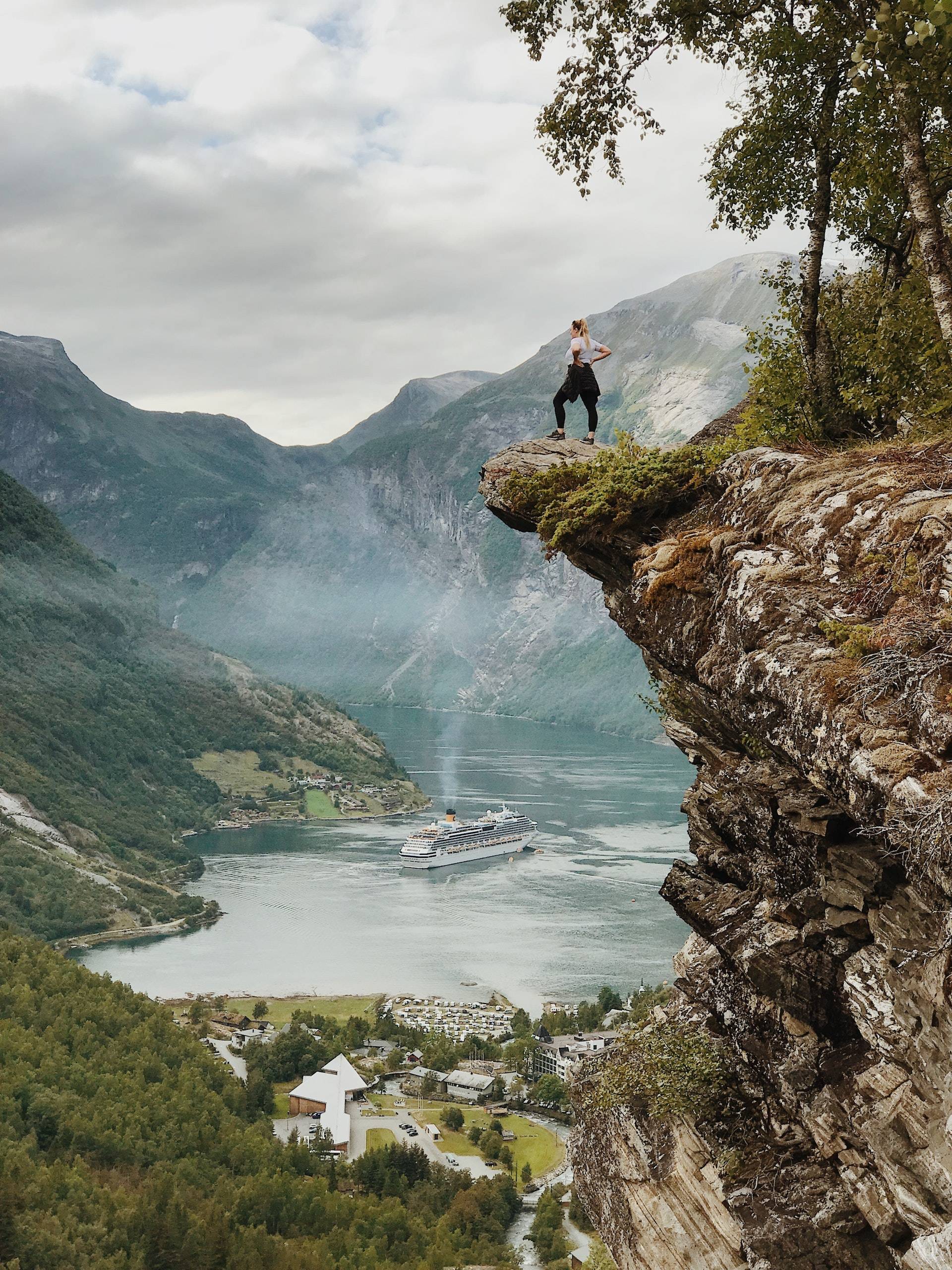 Person standing on a rock ledge overlooking a valley with a town below